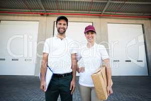 Portrait of delivery man and woman standing with clipboard and parcel