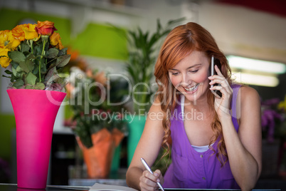 Female florist taking order on mobile phone