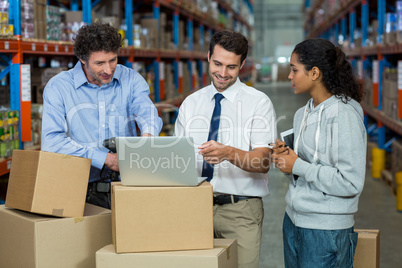 Warehouse manager and worker discussing with laptop