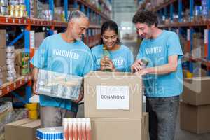 Three volunteers packing eatables in cardboard box