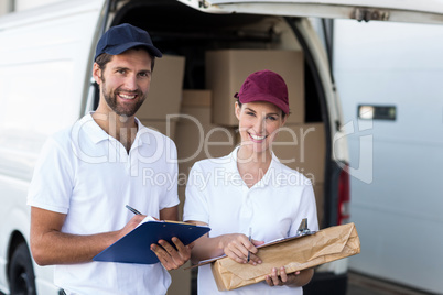 Portrait of delivery man and woman standing with clipboard and parcel