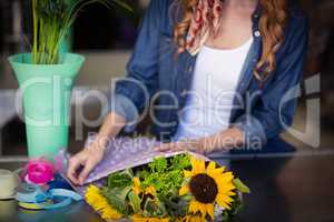 Female florist wrapping flower bouquet
