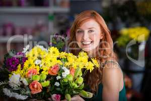 Happy female florist holding bunch of flowers