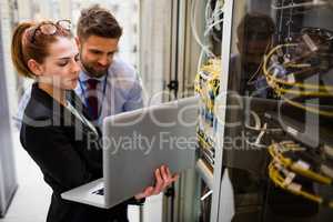 Technicians using laptop while analyzing server