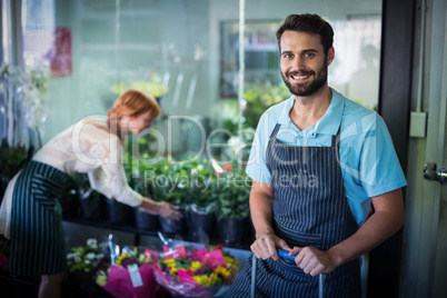 Male florist standing while female florist working in the background