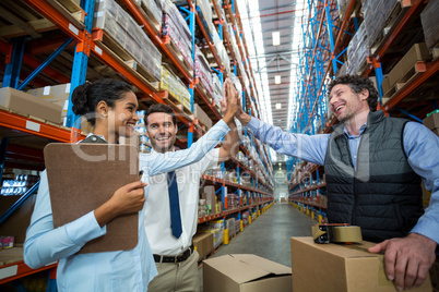 Happy warehouse workers giving high five