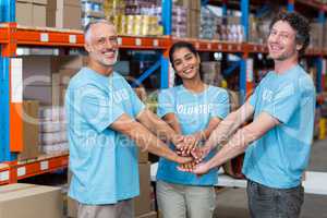 Portrait of happy volunteers putting hands together