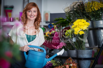 Happy female florist watering flowers