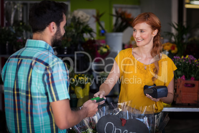 Man making payment with his credit card to female florist