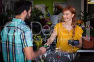 Man making payment with his credit card to female florist