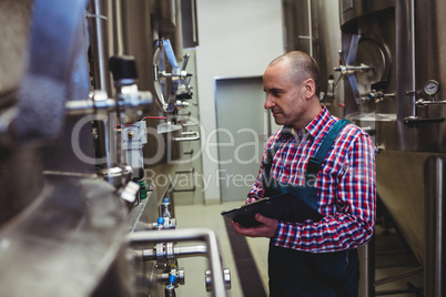 Manufacturer examining machinery at brewery