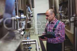 Manufacturer examining machinery at brewery