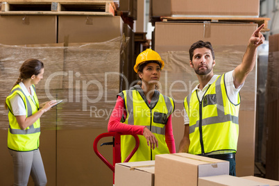 Warehouse workers discussing while preparing a shipment