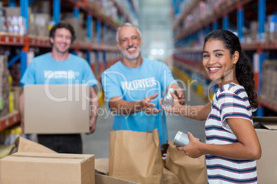 Three volunteers packing eatables in cardboard box