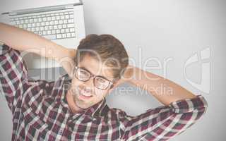 Composite image of creative businessman smiling while lying by laptop on hardwood floor