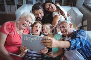 Multi-generation family taking a selfie on digital tablet in living room