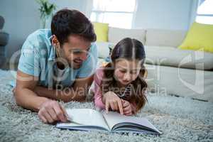 Father and daughter reading book in the living room
