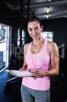 Happy fitness instructor holding clipboard in gym