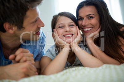 Parents and daughter lying in bedroom