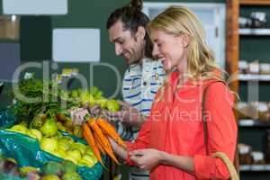 Happy couple selecting fruits and carrots in organic section