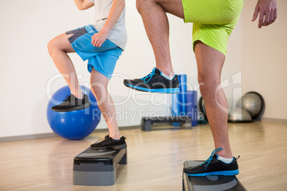 Two men doing step aerobic exercise on stepper