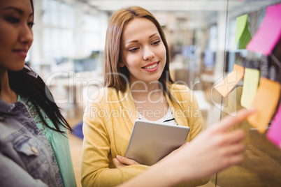 Photo editor with female coworker looking at sticky notes