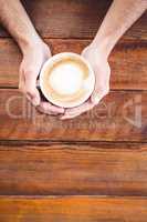 Hands holding a coffee cup on a table