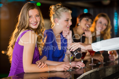 Waiter pouring cocktail in womans glass at bar counter