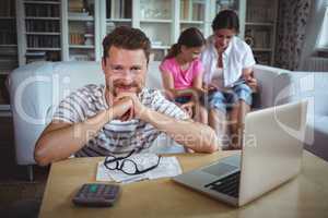Smiling man sitting at table with bills and laptop