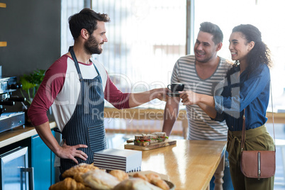 Waiter serving a coffee to customer at counter