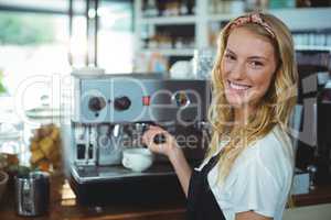 Portrait of smiling waitress making cup of coffee