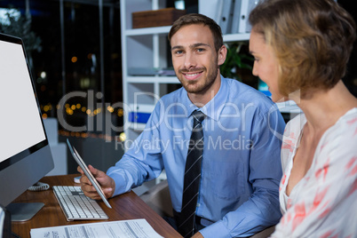 Businessman discussing with colleague over digital tablet