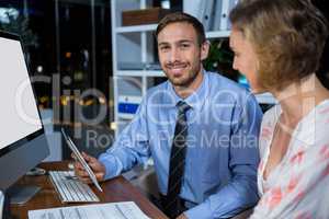 Businessman discussing with colleague over digital tablet