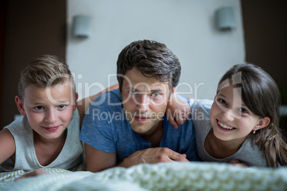 Portrait of father and kids lying in bedroom