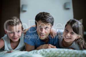 Portrait of father and kids lying in bedroom