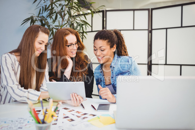 Smiling businesswomen looking at digital tablet at desk