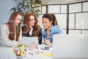Smiling businesswomen looking at digital tablet at desk