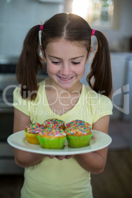 Girl holding a plate of cupcakes