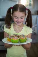 Girl holding a plate of cupcakes