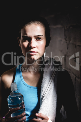 Serious female athlete holding water bottle