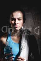 Serious female athlete holding water bottle