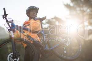 Female biker carrying mountain bike and walking