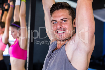 Portrait of smiling man doing chin-ups in gym