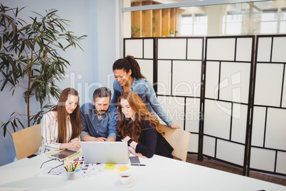 Creative business people using laptop in meeting room