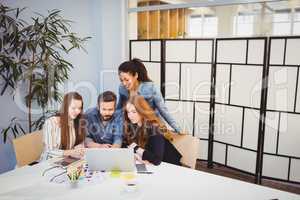 Creative business people using laptop in meeting room