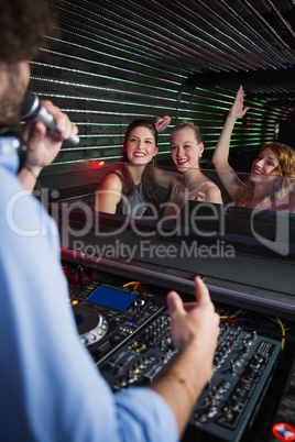 Male disc jockey playing music with three women dancing on the dance floor