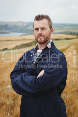 Portrait of farmer standing with arms crossed in the field