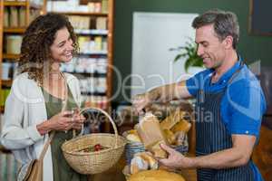Smiling woman purchasing bread at bakery store