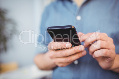 Midsection of businessman texting on cellphone at creative office