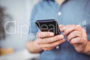 Midsection of businessman texting on cellphone at creative office